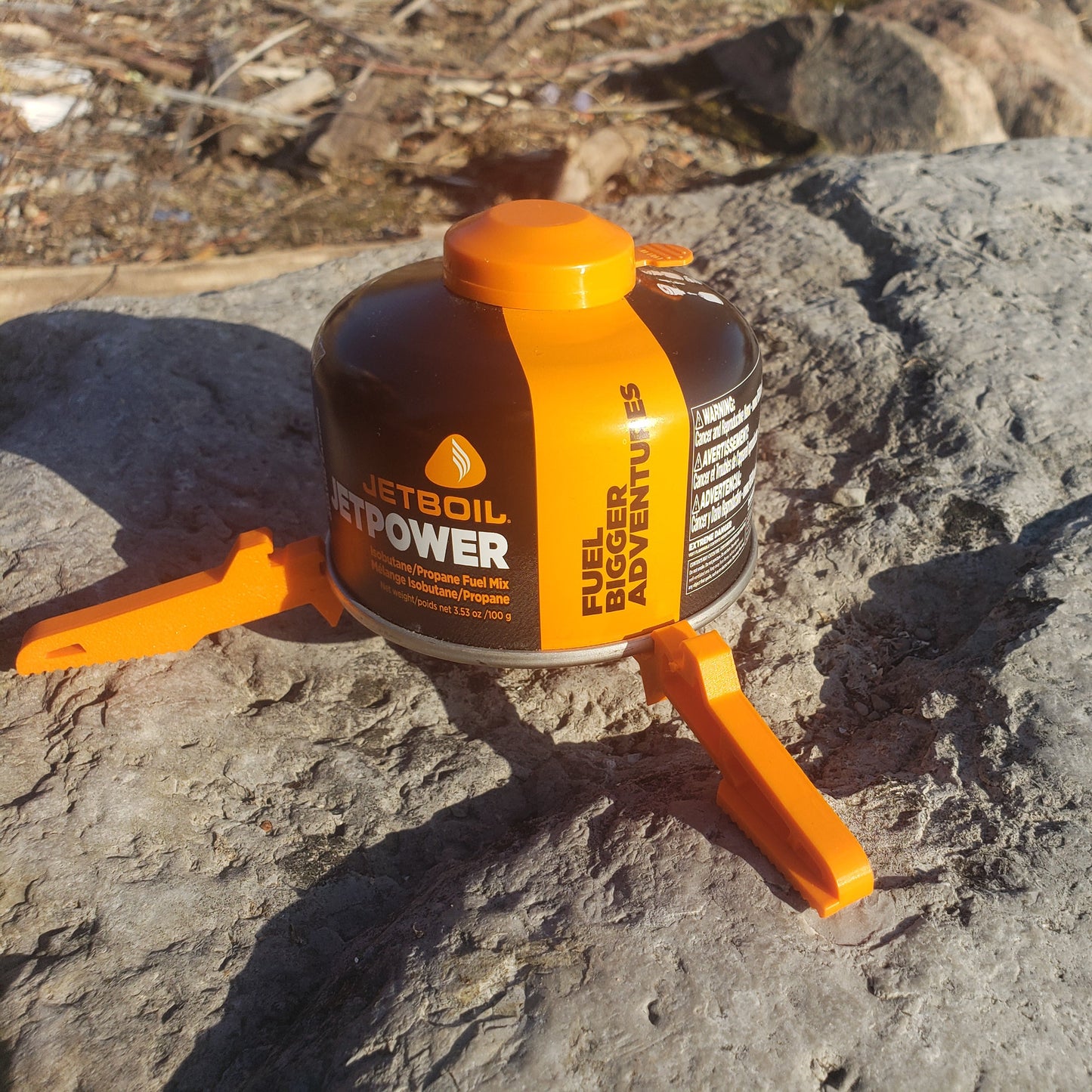 Fuel canister with orange nozzle on a rocky surface